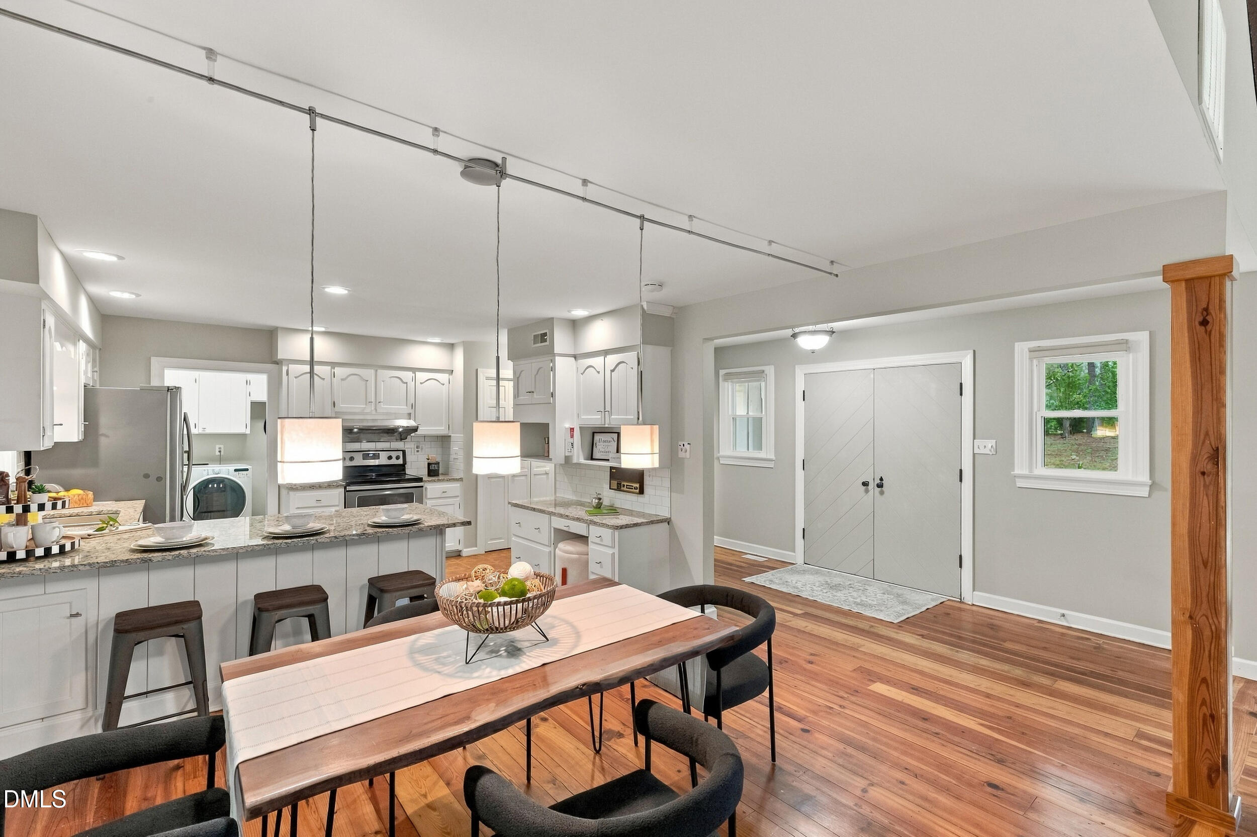 2329 Win Road Garner, NC 27529 - Photo 28 of 90 Open-concept kitchen and dining area featuring wood-finish flooring, white cabinetry, a kitchen island with granite countertops, and stainless steel appliances