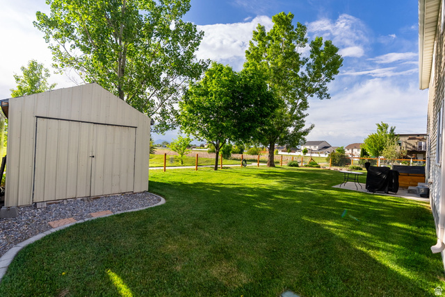 2485 South 1100th Street West Logan, UT 84321 - Photo 36 of 53 Expansive green lawn featuring a storage shed with double doors, bordered by a gravel and paver pathway