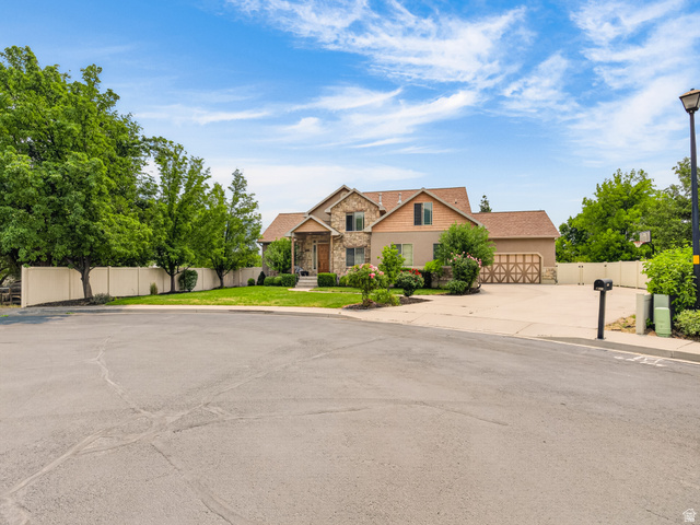 1279 West 1500th Street North Mapleton, UT 84664 - Photo 82 of 83 Stucco and stone exterior featuring a covered front porch, an attached garage with decorative wood-finish doors, a concrete driveway, and mature landscaping