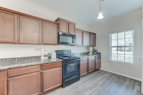 a kitchen with stainless steel appliances granite countertop a stove a sink and white cabinets