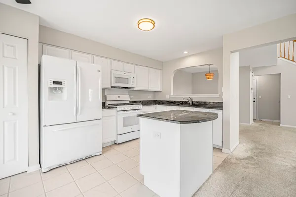 a kitchen with granite countertop a refrigerator sink stove and cabinets