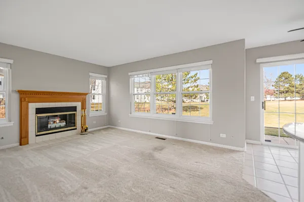 an empty room with windows and fireplace