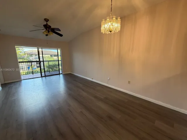 a view of a livingroom with a chandelier wooden floor and windows
