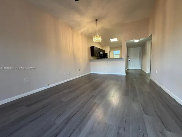 a view of a big room with wooden floor a ceiling fan and a kitchen