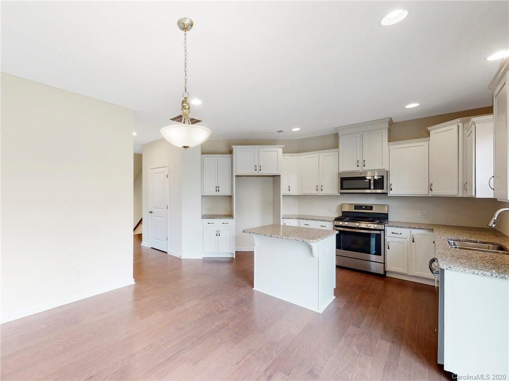 713 Swift Run Tega Cay, SC 29708 - Photo 4 of 8 a kitchen with stainless steel appliances granite countertop a sink a stove a refrigerator cabinets and living room view