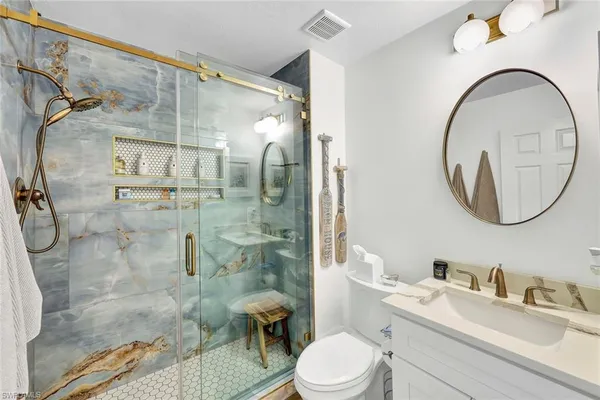 a bathroom with a toilet sink vanity granite and shower