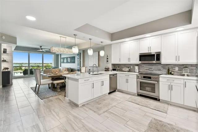 a open kitchen with stainless steel appliances granite countertop a stove top oven a sink dishwasher a dining table and chairs with wooden floor