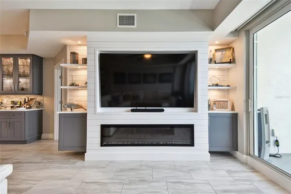 a living room with stainless steel appliances wooden floor and a fireplace
