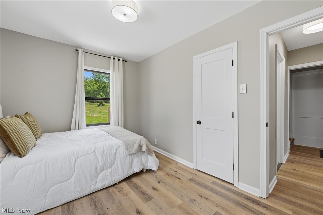 951 Bey Road Akron, OH 44312 - Photo 18 of 34 First floor bedroom featuring wood-finish flooring, a contemporary ceiling light fixture, a window with exterior views, and a solid core door with matte black hardware