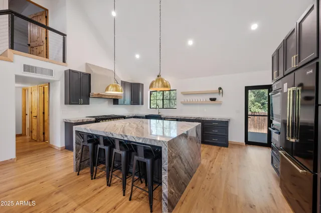 a kitchen with stainless steel appliances granite countertop a kitchen island hardwood floor and a sink