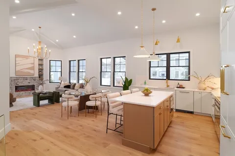 a large dining hall with stainless steel appliances kitchen island a stove a sink a refrigerator and a dining table view