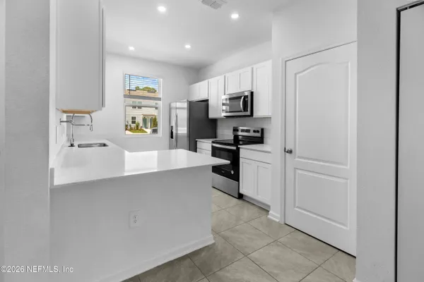 a large white kitchen with cabinets and stainless steel appliances