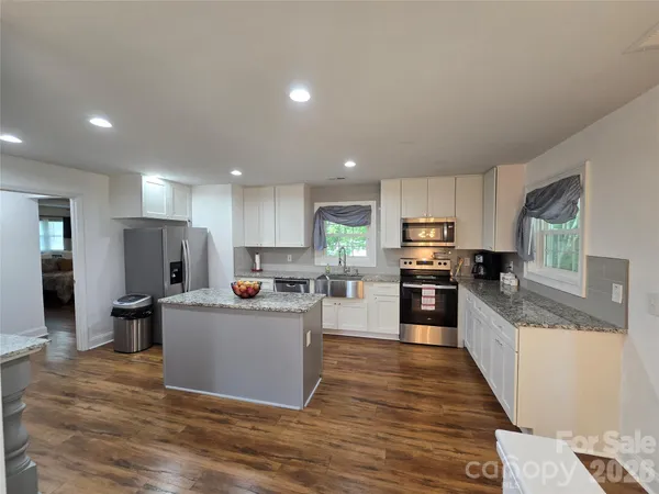 a kitchen with kitchen island counter top space a sink stainless steel appliances and cabinets