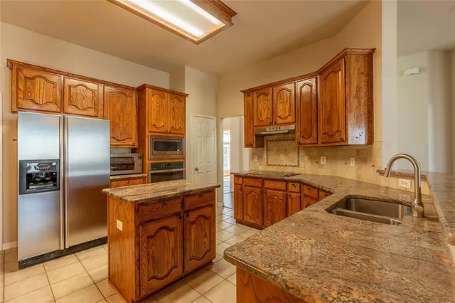 a kitchen with stainless steel appliances granite countertop a sink refrigerator and cabinets