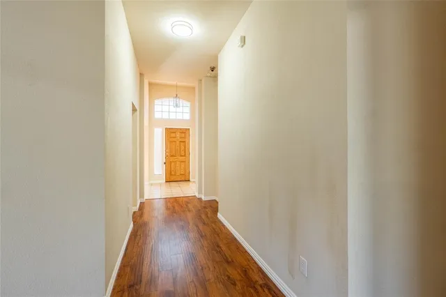 a view of a hallway with wooden floor and a bathroom