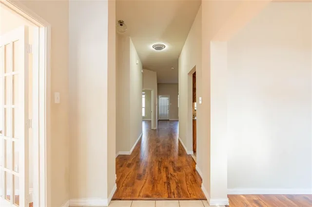 a view of a hallway with wooden floor and a bathroom