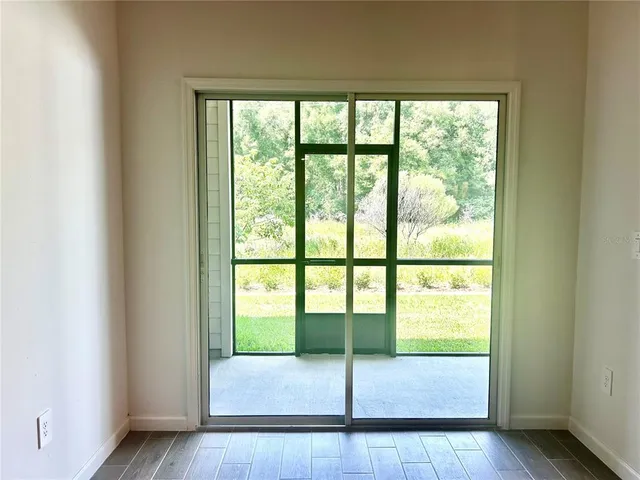 a view of an empty room with wooden floor and windows
