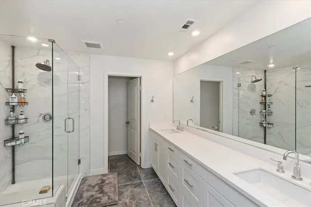 a bathroom with a double vanity sink mirror and shower
