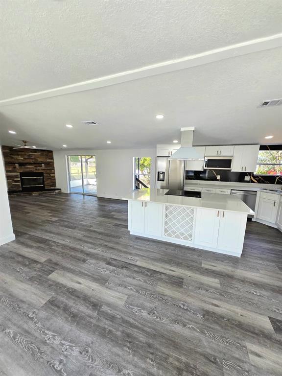 4928 Rollinglen Loop East Lakeland, FL 33810 - Photo 23 of 44 a large kitchen with granite countertop a stove top oven a sink dishwasher and a fireplace with wooden floor