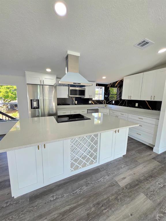 4928 Rollinglen Loop East Lakeland, FL 33810 - Photo 33 of 44 a large kitchen with stainless steel appliances kitchen island granite countertop a stove a sink a refrigerator and white cabinets with wooden floor