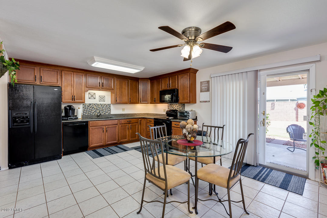 3452 East Nisbet Road Phoenix, AZ 85032 - Photo 11 of 31 a kitchen with stainless steel appliances kitchen island granite countertop a refrigerator a sink a stove with a dining table and chairs