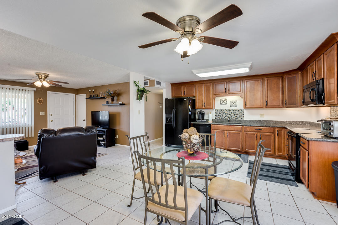 3452 East Nisbet Road Phoenix, AZ 85032 - Photo 12 of 31 a kitchen with stainless steel appliances kitchen island granite countertop a refrigerator a stove a sink dishwasher and a dining table with wooden floor