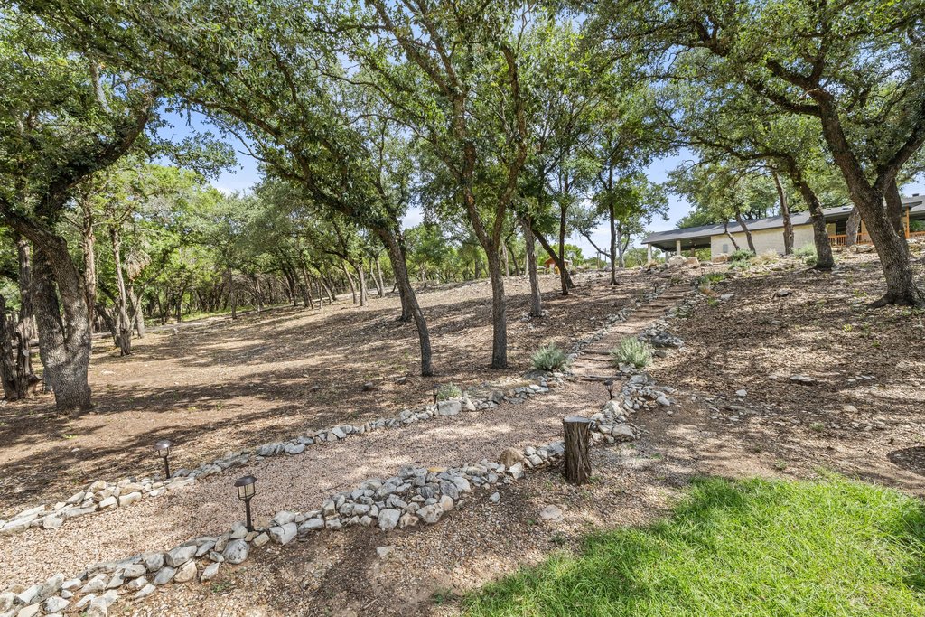 23644 Nameless Road Leander, TX 78641 - Photo 21 of 40 A meandering stone path leads up a gentle slope towards a home nestled amongst mature trees.
