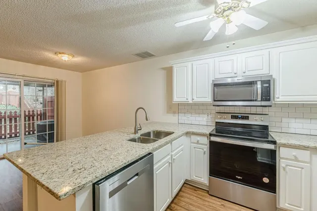 a kitchen with granite countertop a sink cabinets and stainless steel appliances
