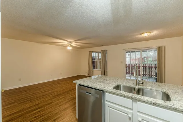 a kitchen with granite countertop a sink and dishwasher with wooden floor