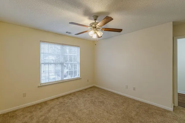 an empty room with windows and fan