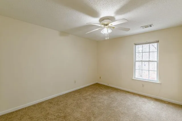 an empty room with windows and fan