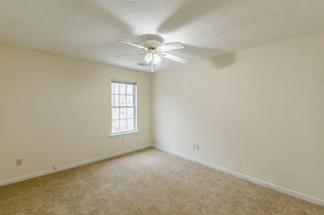 an empty room with windows and fan