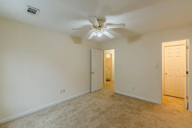 an empty room with closet and a ceiling fan