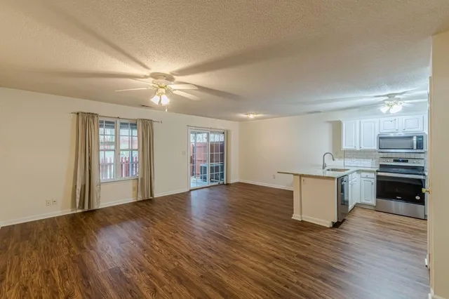 a view of an empty room with window and wooden floor
