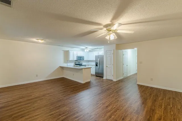 a view of kitchen and empty room with wooden floor