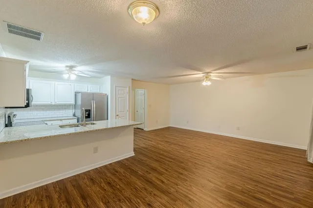 a view of kitchen and empty room with wooden floor