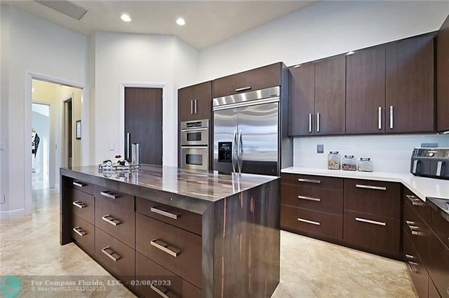 a kitchen with stainless steel appliances kitchen island granite countertop a refrigerator and cabinets