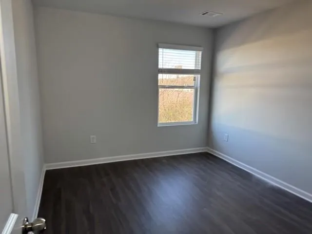 an empty room with wooden floor and a window