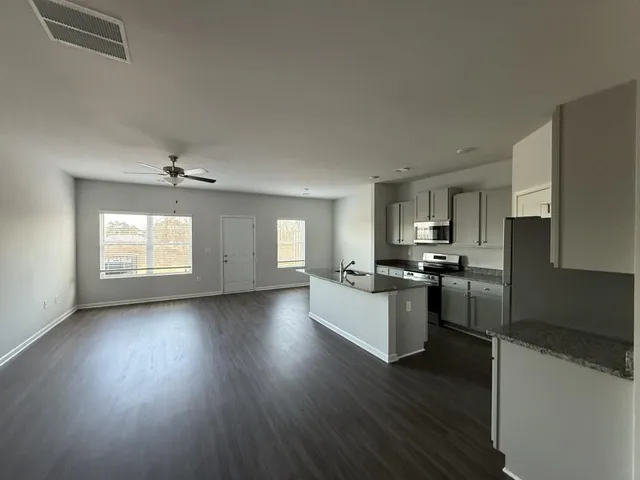 a kitchen with granite countertop a stove top oven a sink dishwasher and a refrigerator with wooden floor