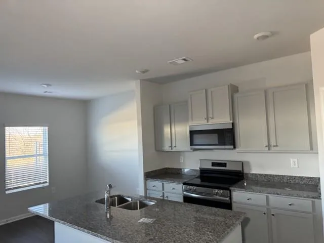 a kitchen with granite countertop a stove a sink and a granite counter tops