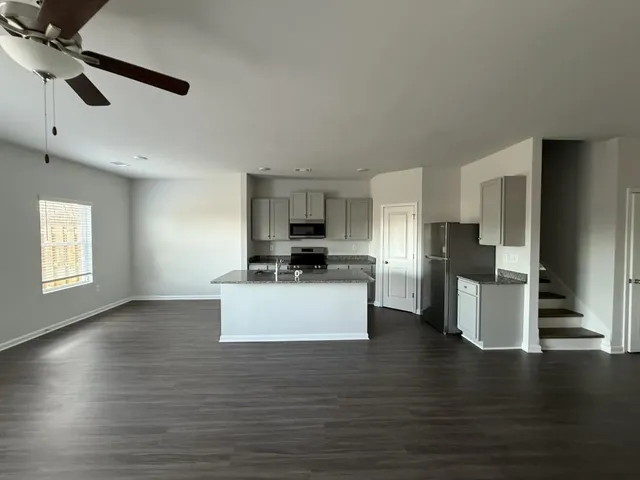 a view of kitchen with stainless steel appliances kitchen island wooden floors granite counter tops and a view of living room