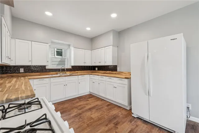 a open kitchen with white cabinets and wooden floor