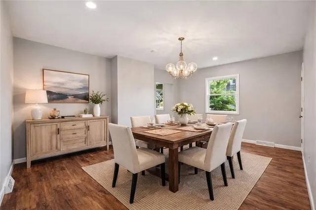 a dining room with wooden floor a chandelier a wooden table and chairs