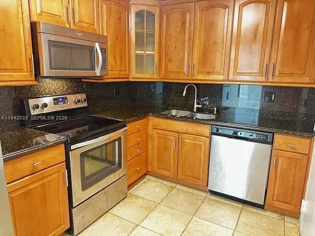 a kitchen with granite countertop cabinets stainless steel appliances and a counter space