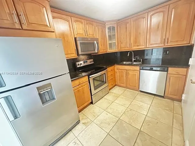 a kitchen with stainless steel appliances granite countertop a refrigerator sink stove and microwave