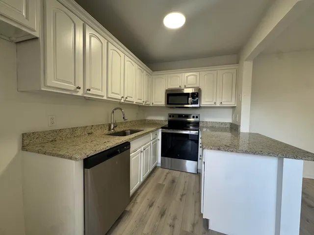 a kitchen with kitchen island granite countertop a sink a counter top space stainless steel appliances and cabinets