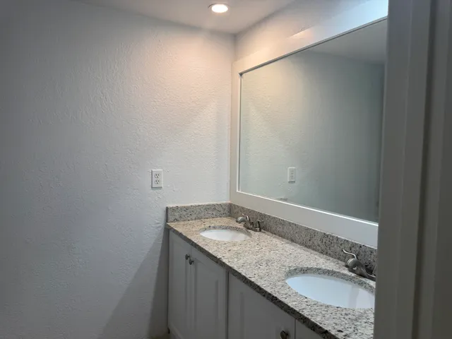 a bathroom with a granite countertop sink and a mirror