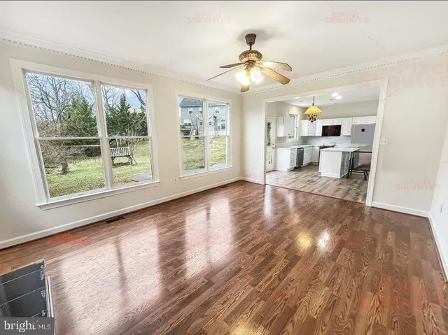 a view of empty room with wooden floor and fan