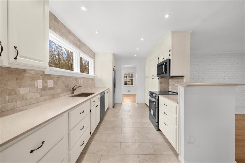 4890 High Point Road Northeast Sandy Springs, GA 30342 - Photo 11 of 35 a large kitchen with stainless steel appliances kitchen island granite countertop a sink and dishwasher with white cabinets