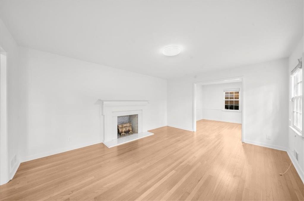 4890 High Point Road Northeast Sandy Springs, GA 30342 - Photo 6 of 35 a view of empty room with wooden floor and fireplace